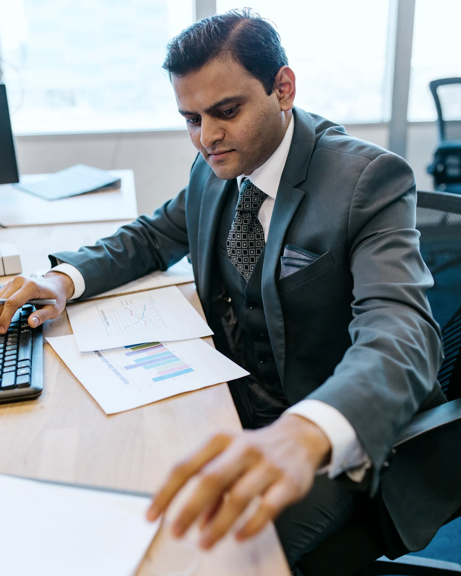 An auditor reviewing chart data at his desk, pen in hand.