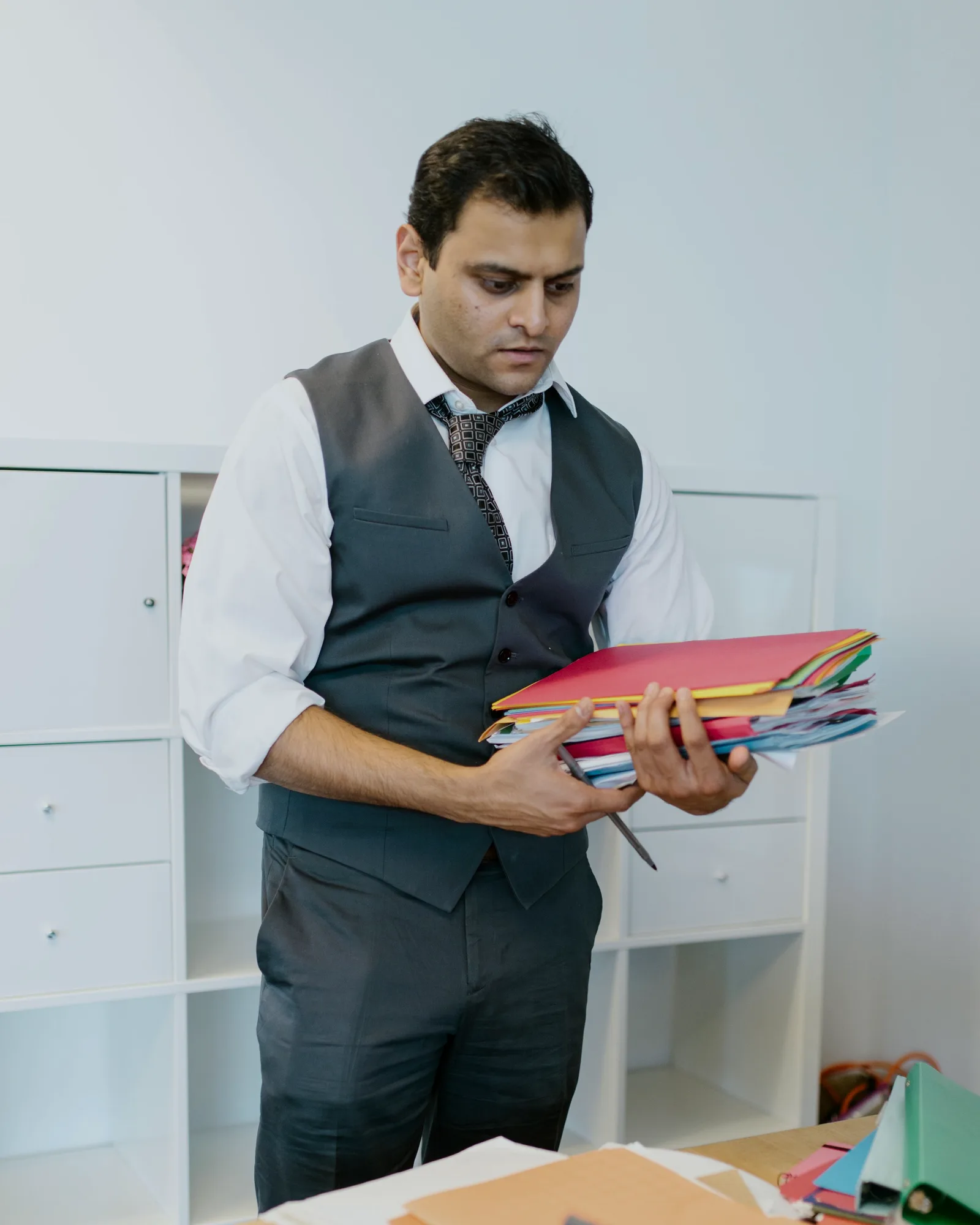 An accountant holding a stack of colour-coded client folders.