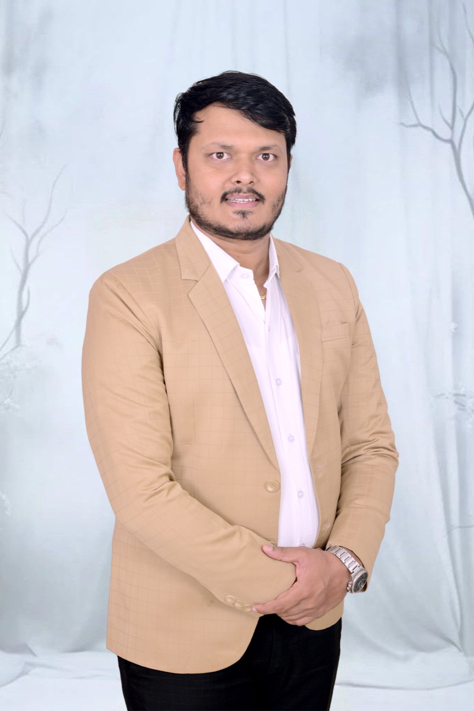 CA Devendra Kumar Jain, founder of Saramis Global, in a tan jacket against a pale studio backdrop.